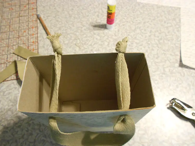 Make a Recycled Gift Bag threading ribbon through holes to make handles