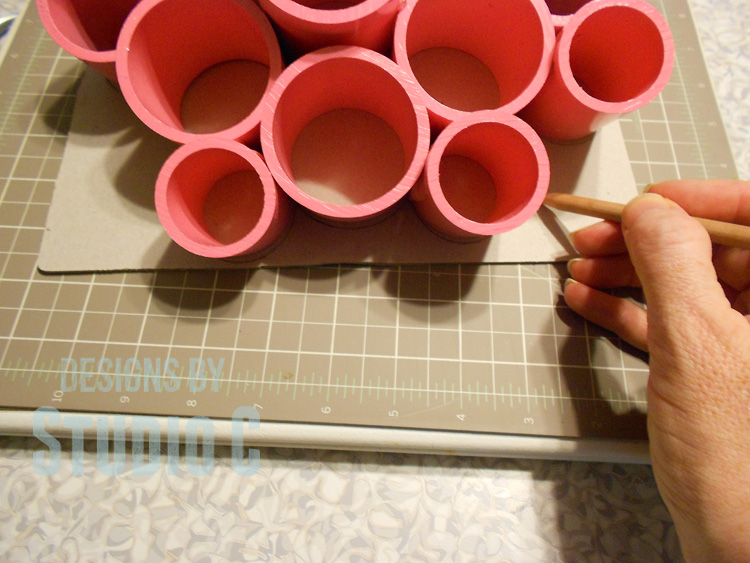 make desk organizing cups with pvc tracing bottom on piece of cardboard