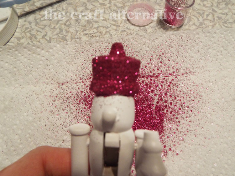 DIY Painted Nutcrackers with Glitter Hats apply glitter over the Mod Podge