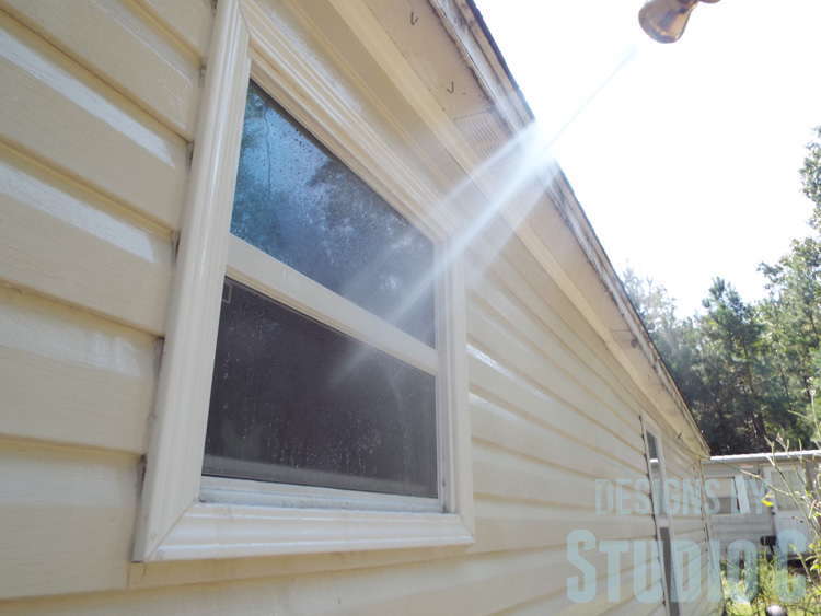 cleaning-exterior-vinyl-trim-windows-spray-nine rinsing window with water